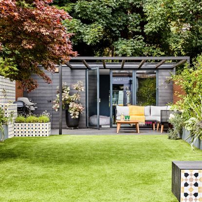 Garden shed with lawn surrounding, trees, plants in planters