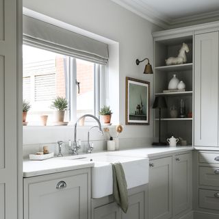 a neutral shaker-style kitchen with a butler sink beside a window