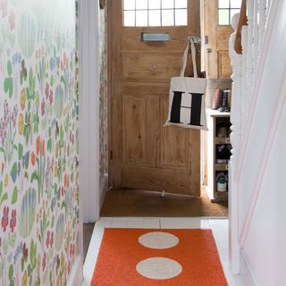 front door and hallways with multicoloured floral wallpaper and an orange runner