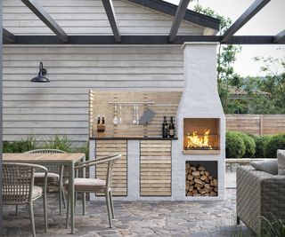 An outdoor kitchen area with a wood burning stove along with wood storage and a handy screen for hanging up utensils
