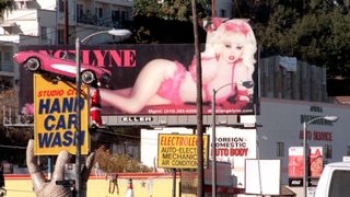 A 1962 Chevrolet Corvette is mounted on top of The Studio City Hand Car Wash and a poster of Angelyne is behind December 17, 1999 in Studio City, Los Angeles, California .