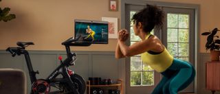 a photo of a woman doing a workout with the peloton bike plus