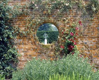 The sundial at Polesden Lacey, Surrey, seen through a circular portal in a garden wall