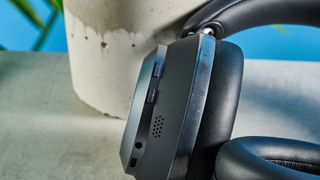 the soundcore space one pro headphones; a photograph of a pair of black over-ear headphones with cushioned cups and a soft headband, photographed in front of a blue background