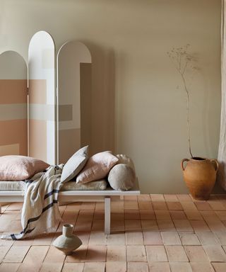 painted screen with cushions on daybed and terracotta tiled floor