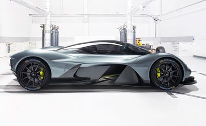 The side view of a greyish-blue Aston Martin Valkyrie photographed in a white automechanic space