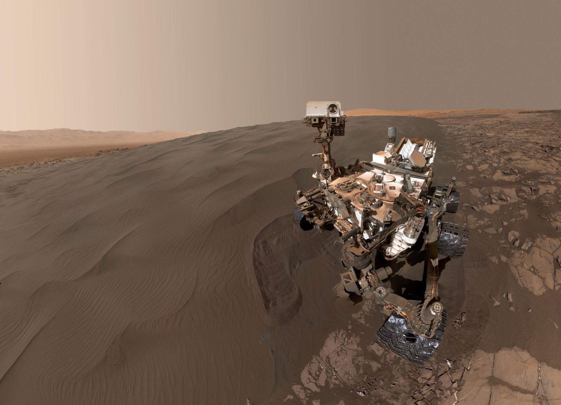 A rover is seen on a muddy brown surface.