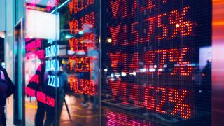 A close up shot of a street window display showing a series of falling stock prices