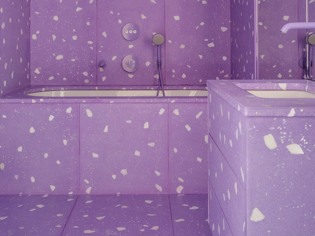 A bathroom with purple tiles with white specks in it