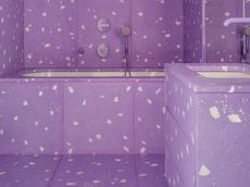 A bathroom with purple tiles with white specks in it
