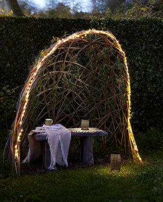 garden arbor ideas: woven arch over bench with lights