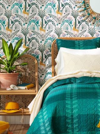 A blue bed with colorful peel and stick wallpaper behind it