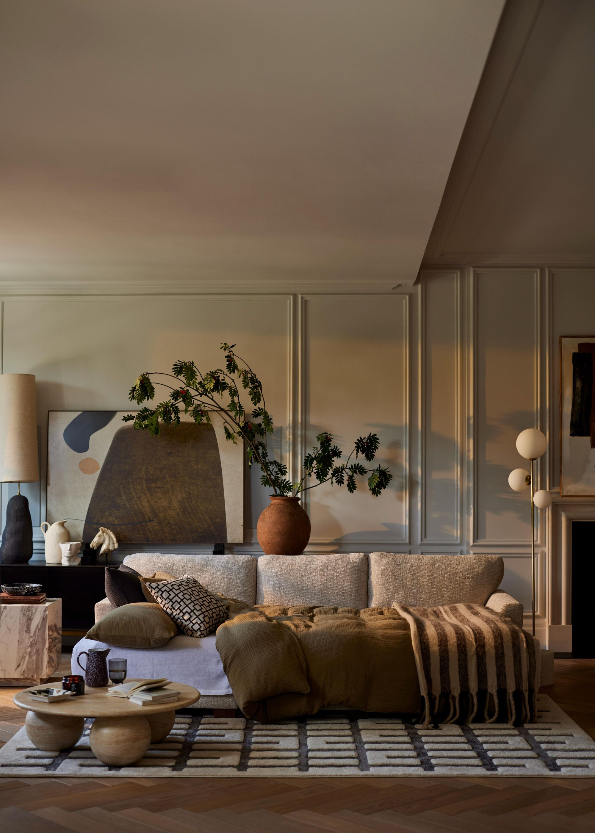 A modern living room with a beige sofa with a temporary bed set-up.