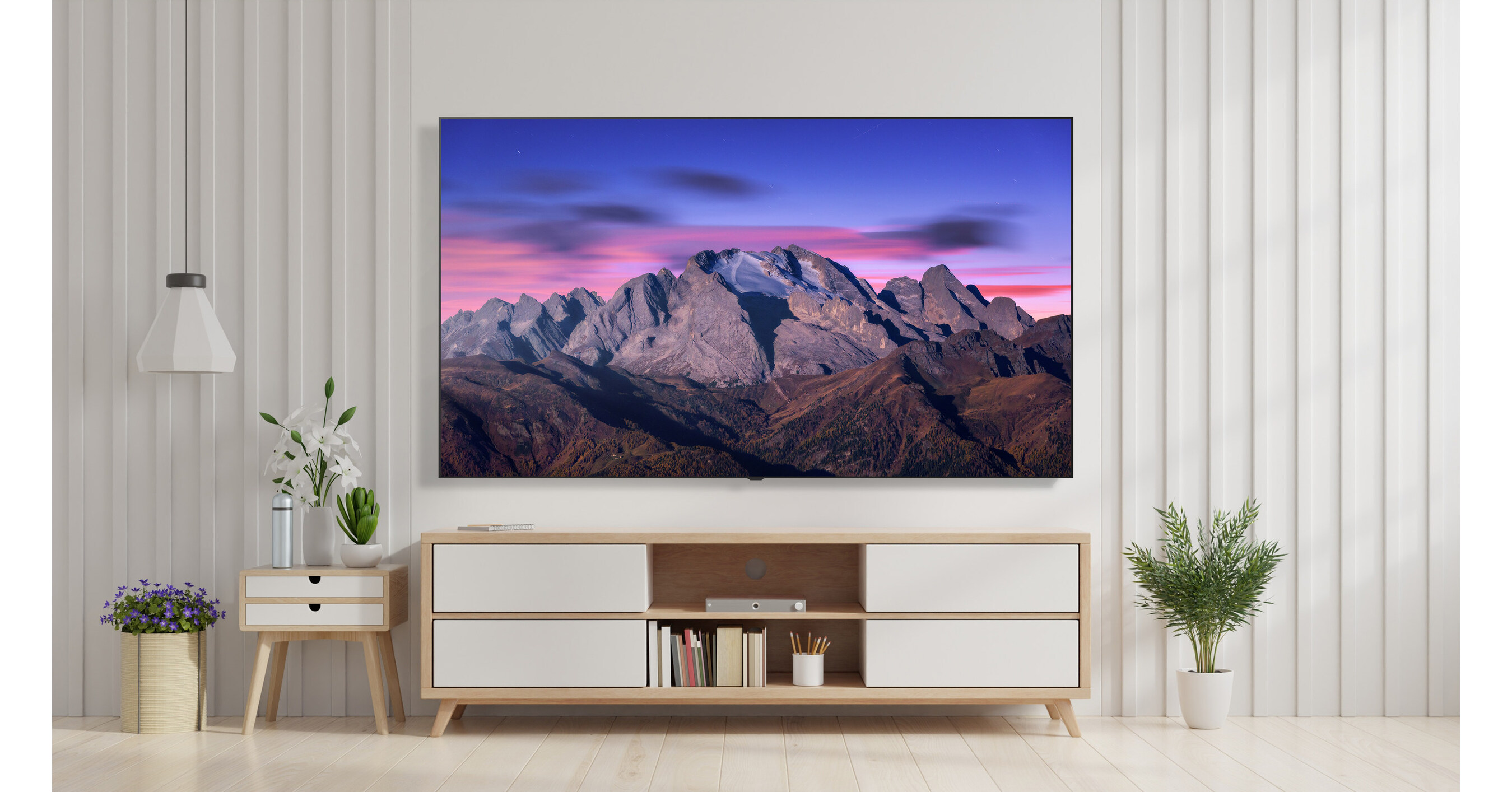 An LG B5 TV showing an image of a mountain range at dusk. The TV is wall mounted in a bright room above a TV unit