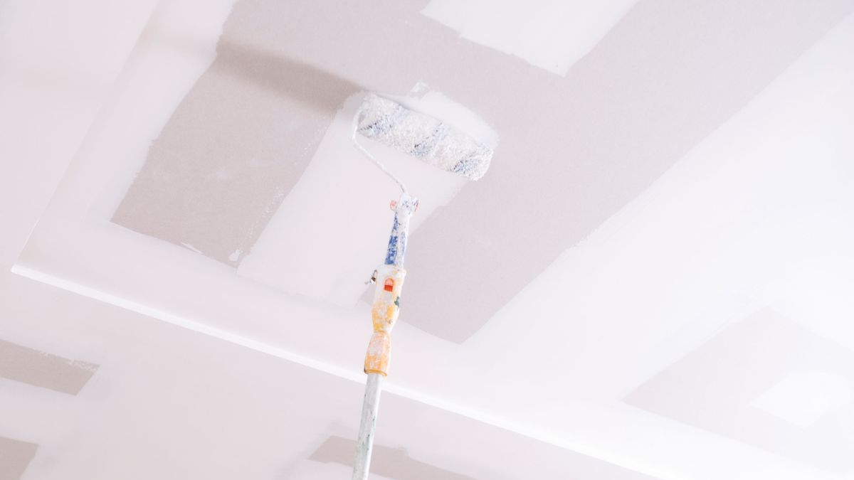 Paint roller painting ceiling white