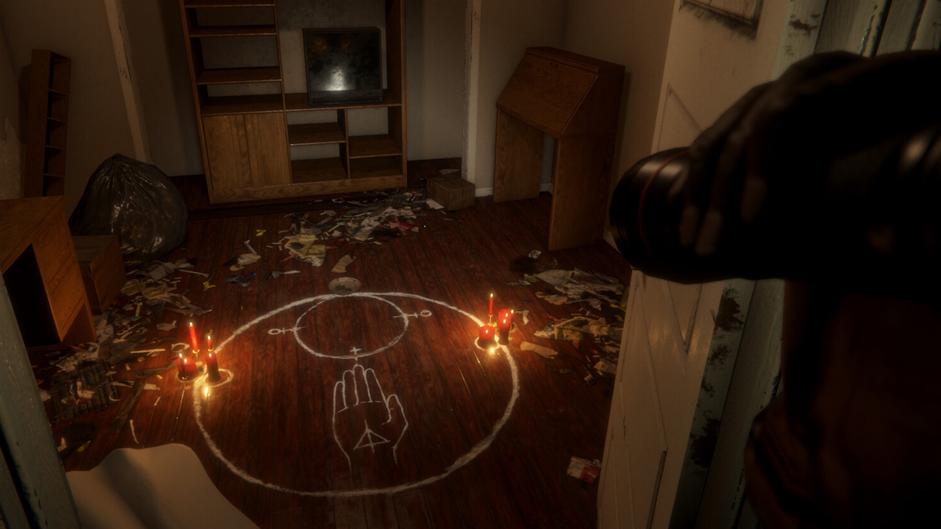 Demonic inscription and candles on the floor of a trash-strewn room