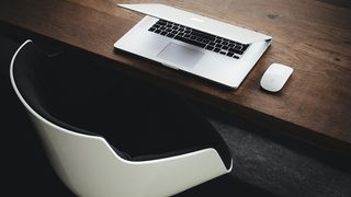 The Apple Magic Mouse next to a MacBook Pro on a desk