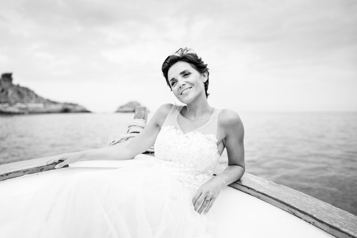 Monochrome image of a woman in white dress sitting in a boat