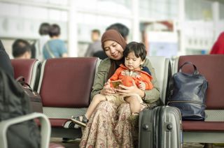 mother and infant sitting in an airport lounge waiting to board their plane