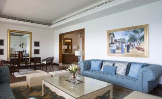 Park Hyatt lounge with blue four seater sofas, cream ottomans, wooden table with glass top, gold framed mirror and painting