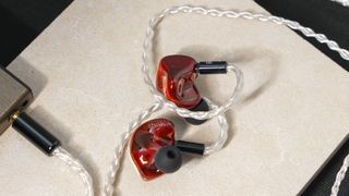 A pair of earbuds from the Zeitgeist Trees collection plugged into a music player.