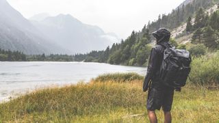 A hiker by a lake in the rain