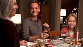 Neil Patrick Harris smiling at the dinner table in 8-Bit Christmas.