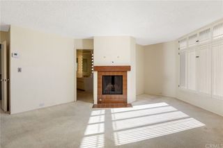 An empty bedroom with cream carpeted floors a tiled fireplace