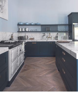 Kitchen flooring ideas in a blue and marble kitchen with herringbone wood flooring.