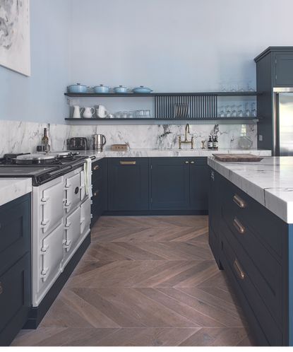 The best kitchen flooring illustrated by wooden herringbone floor in a dark blue and marble kitchen with aga.