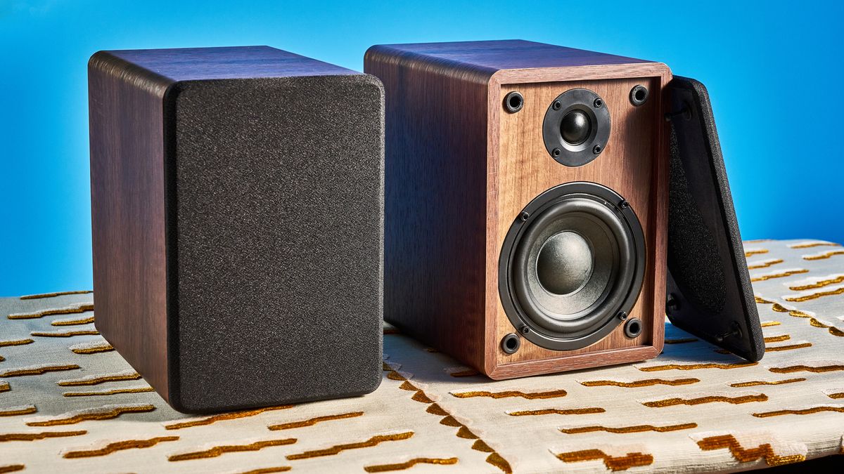 Crosley C65 turntable and bookshelf speakers photographed in front of a blue background on a brown table.