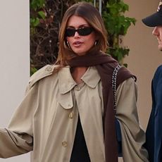 Kaia Gerber's French girl outfit includes a little black dress, a Chanel bag, a timeless trench coat, and ballet flats