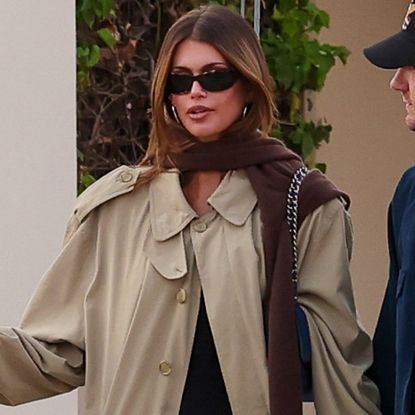 Kaia Gerber's French girl outfit includes a little black dress, a Chanel bag, a timeless trench coat, and ballet flats