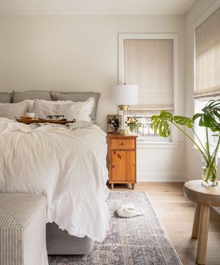 A white bedroom with a gray bed with a white duvet and a gray rug