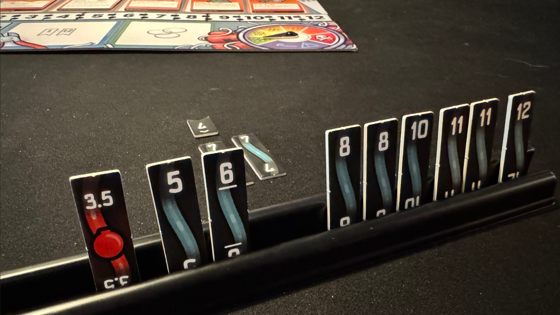 Wire tokens in a stand, with the Bomb Busters board visible in the background, on a black surface