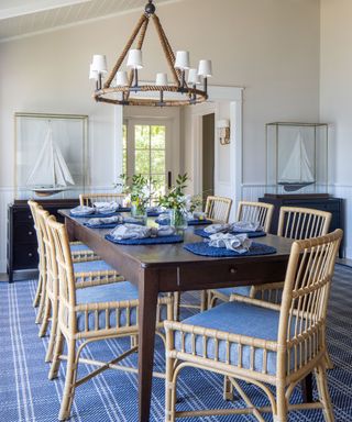 dining room with blue rug and white walls wooden table cane chairs and model yachts
