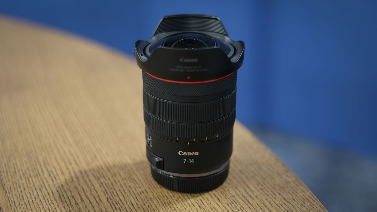 Canon RF 7-14mm f/2.8-3.5L Fisheye STM on a wooden surface in front of a blue background