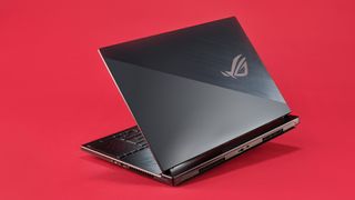 En Asus ROG-laptop visas upp mot en röd bakgrund, med baksidan av laptopen vänd mot kamera och locket öppnat till hälften.