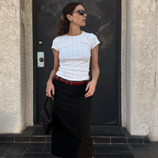 An image of woman wearing red shoes, one of the biggest 2026 shoe color trends, with white t-shirt and black skirt.
