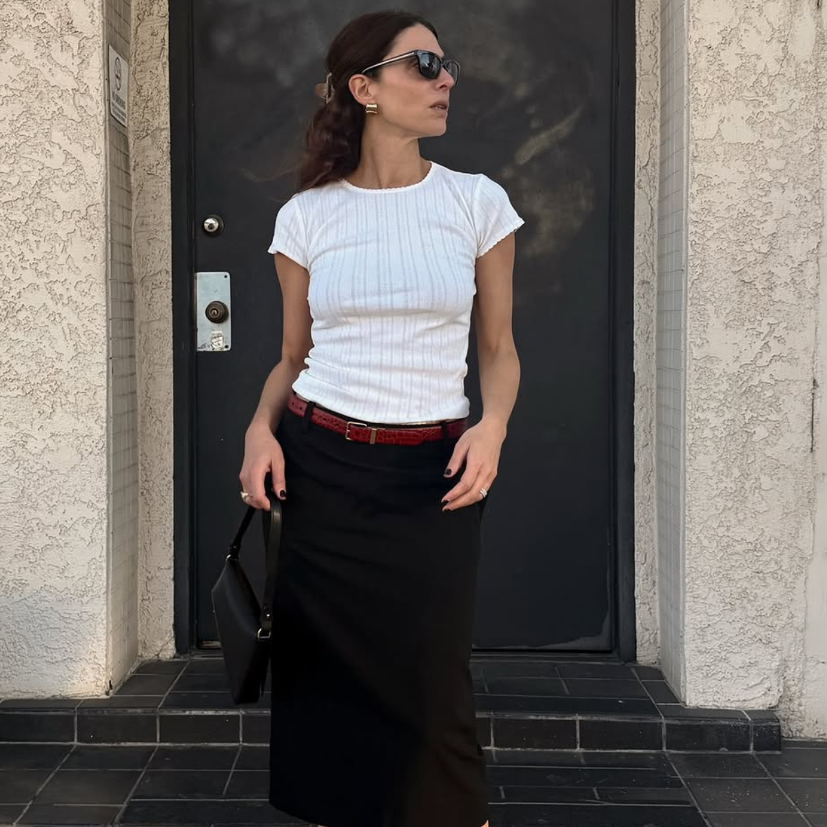 An image of woman wearing red shoes, one of the biggest 2026 shoe color trends, with white t-shirt and black skirt.