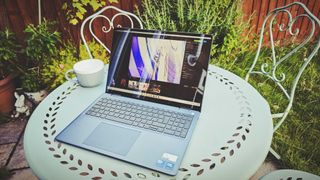 A Dell 16 Plus 2-in-1 laptop on a blue garden table