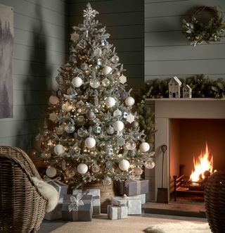 Christmas tree next to fireplace with white and silver baubles