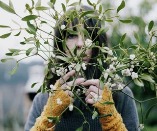 Woman holding a mistletoe branch covered in berries