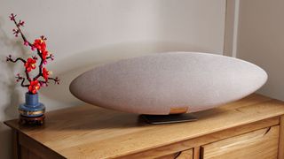 Zeppelin Pro speaker on a wooden surface next to a lego flower