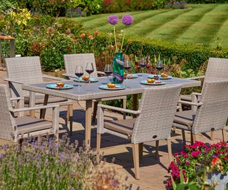 patio with wooden patio furniture and country garden planting