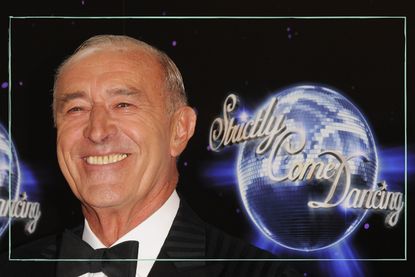 Len Goodman smiling next to a backdrop that reads Strictly Come Dancing