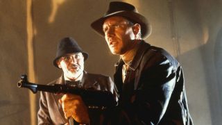 Harrison Ford's Indiana Jones pointing machine gun while Sean Connery Henry Jones watches