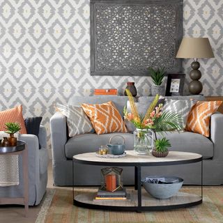 living room with white and grey printed wall and grey sofa with colourful cushion
