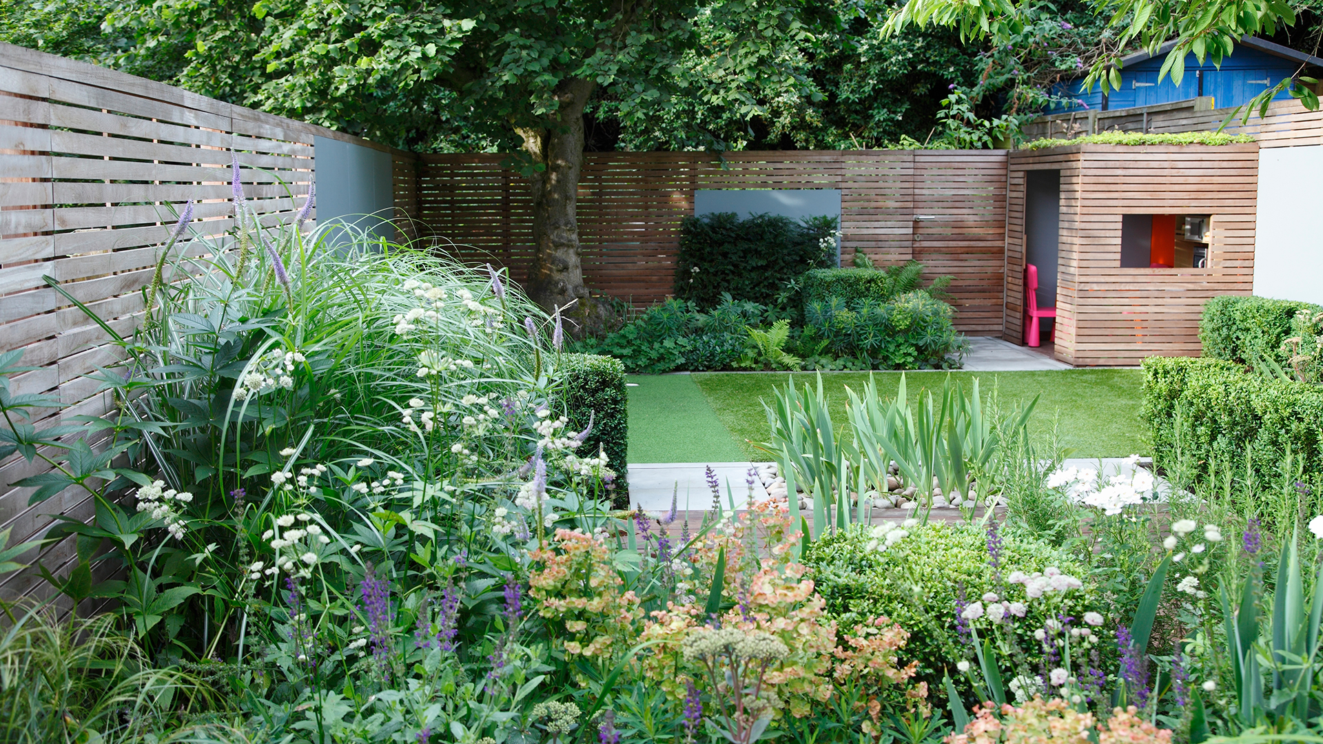 Established garden with flower beds neatly trimmed hedges and a playroom