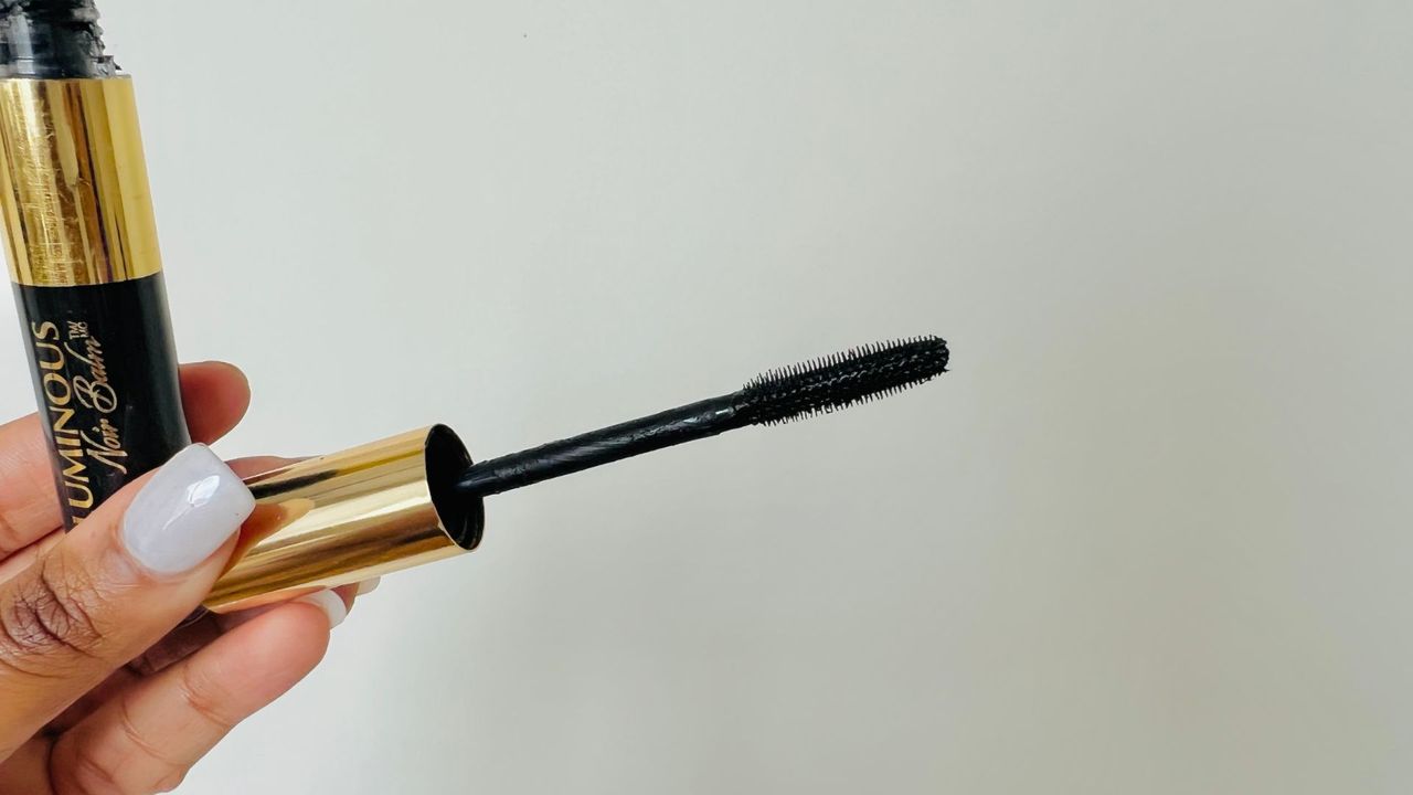 A person holding the L'Oreal Voluminous Noir Balm Mascara wand, for the best L'Oreal mascara.